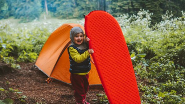 Kind mit Isomatte und Campingausrüstung