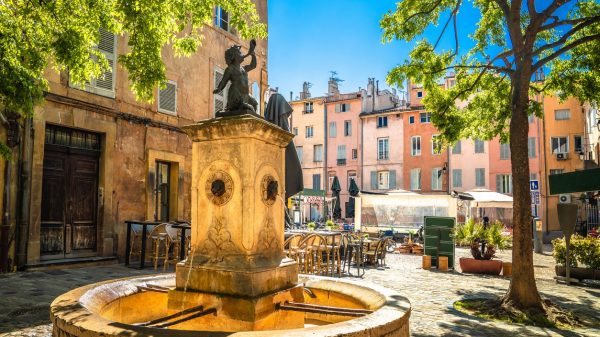 Paysage emblématique de la ville, place bordée de maisons colorées et sa fontaine.
